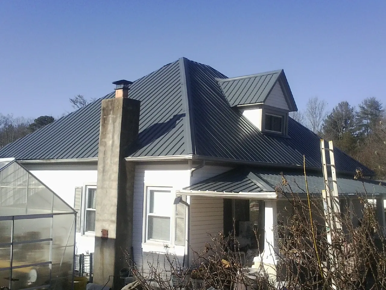 Dark blue standing seam metal roof on a white farmhouse with dormer — Slate & Tile Roof Repair by Roofing Brothers in Pullman