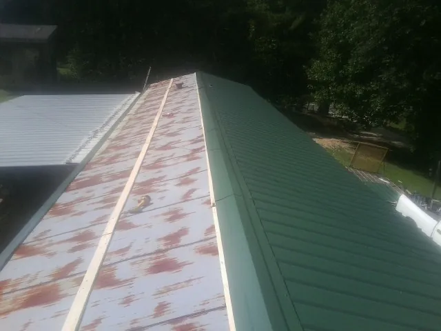 Old rusted panels beside newly installed green metal roofing — Wind Damage Roof Repair by Roofing Brothers in Pullman