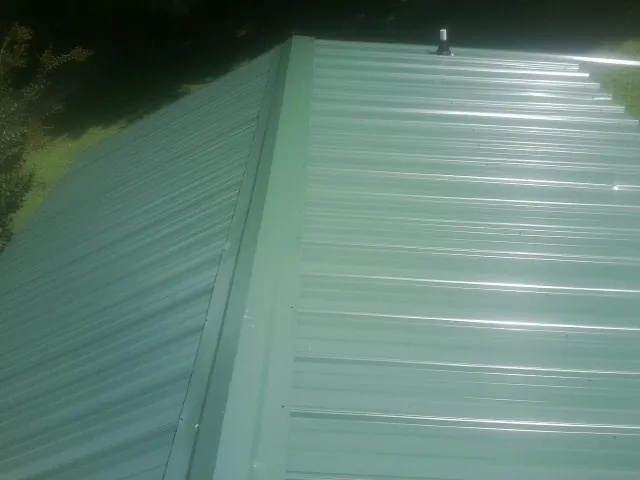 New green metal panels meeting at the ridge of a roof — Flat Roof Repair work by our crew in Pullman